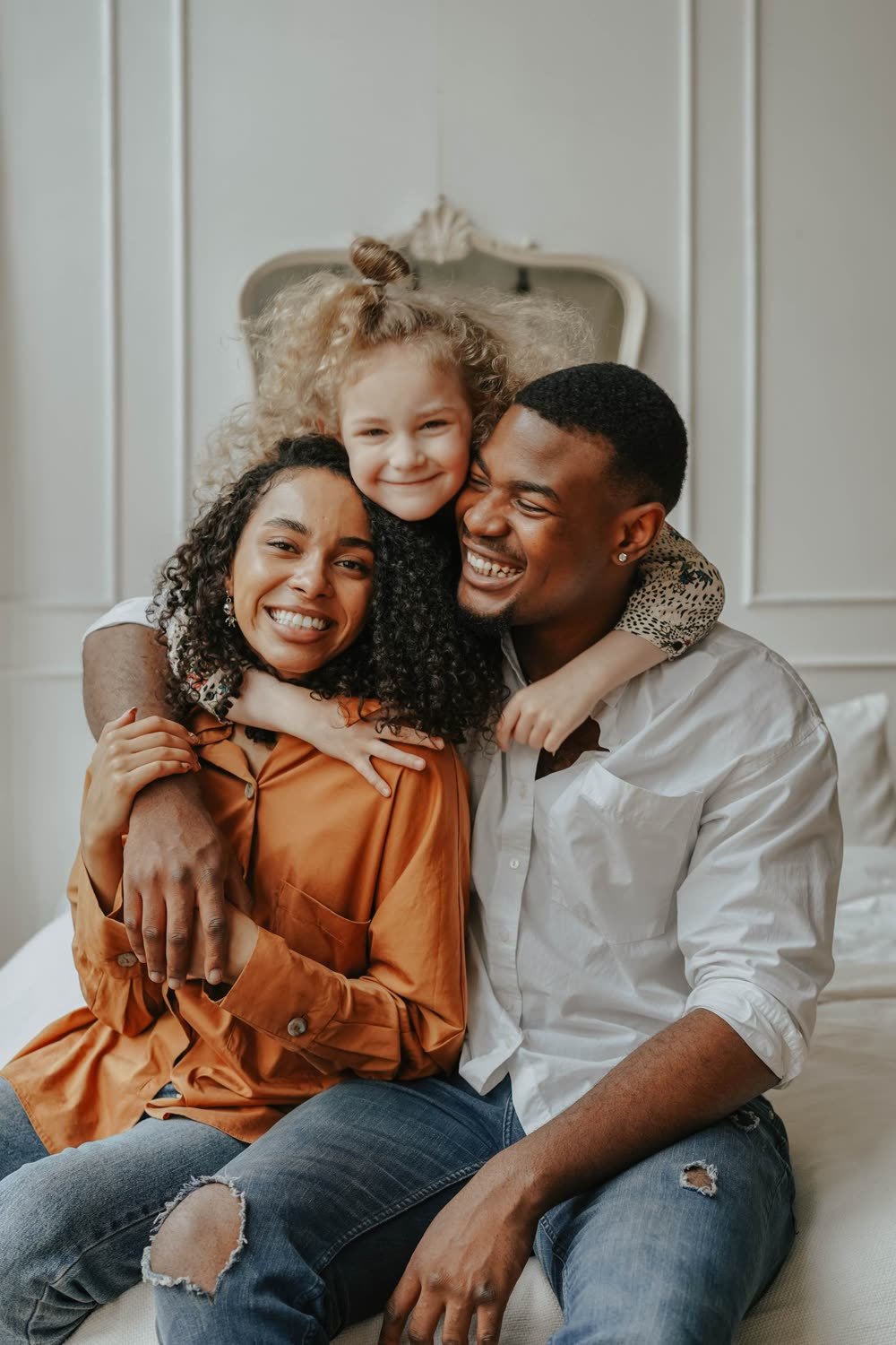 Pai, mãe e filha abraçados, a sorrir